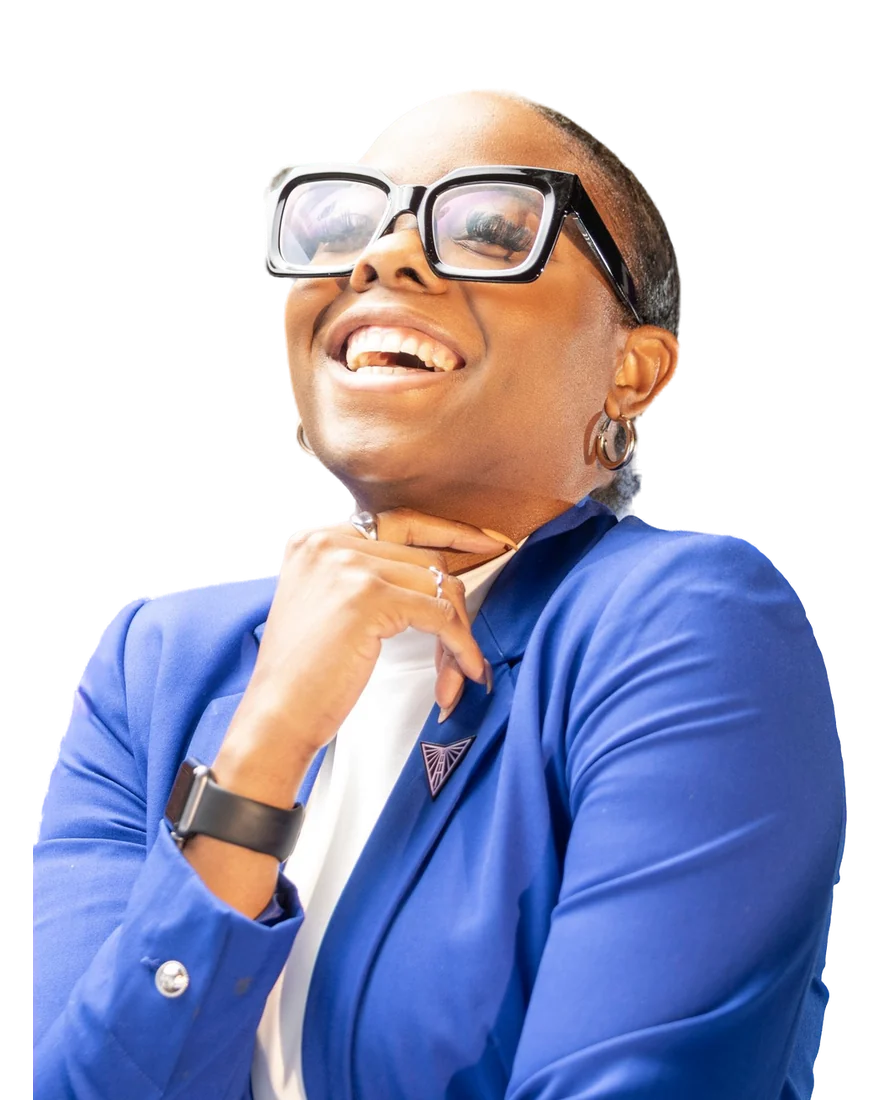 Woman in a cobalt blazer and bold glasses, laughing, hand under her chin